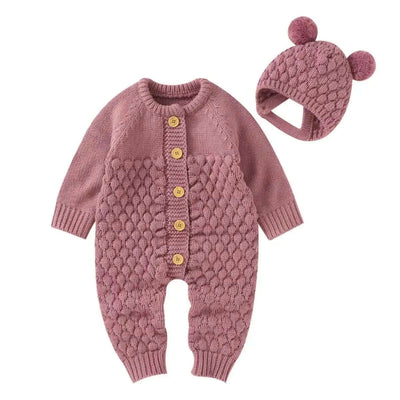 Pink knitted romper with bear ear hat, button closure, and pom-pom details for babies aged 0-24 months.